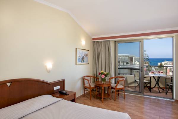 Zimmer mit Balkon und Meerblick im Hydramis Palace Beach Resort mit Tisch, Stühlen und Blick auf das Meer.