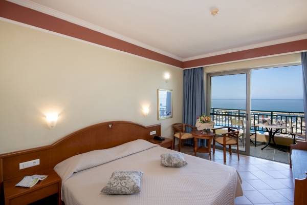 Zimmer im Hydramis Palace Beach Resort mit Meerblick, Bett, Balkon und Tisch.
