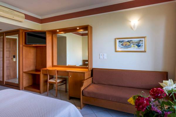 Ein Zimmer im Hydramis Palace Beach Resort mit einem Bett, einem Schreibtisch, einem Spiegel und einem Sofa.