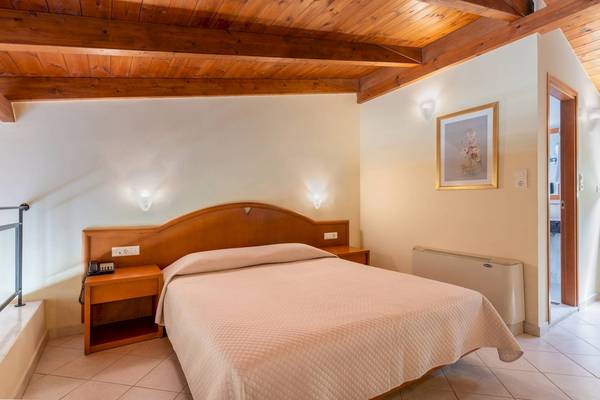 Doppelzimmer mit Holzdecke, Doppelbett, Nachttischen und einem Badezimmer