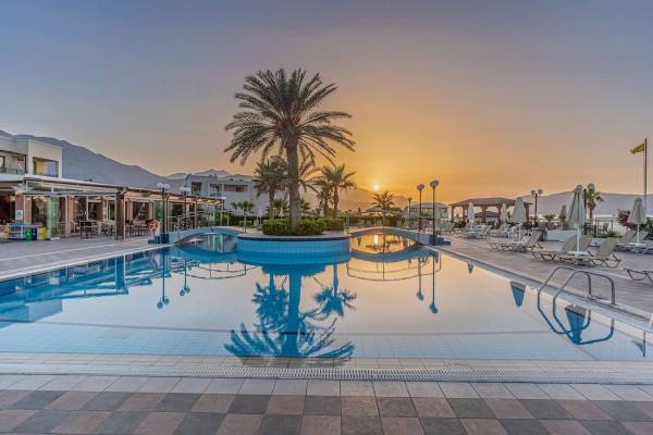 Hydramis Palace Beach Resort Pool bei Sonnenuntergang mit Palmen und Liegestühlen