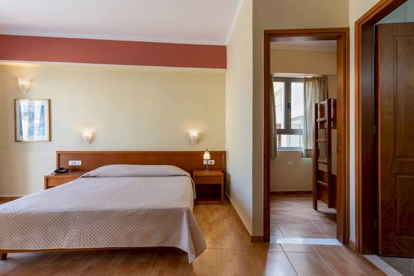 Ein Hotelzimmer im Hydramis Palace Beach Resort mit einem Bett, Nachttischen und offenen Türen.