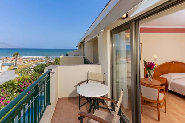 Balkon mit Meerblick im Hydramis Palace Beach Resort, mit Tisch, Stühlen und Blumenvase.