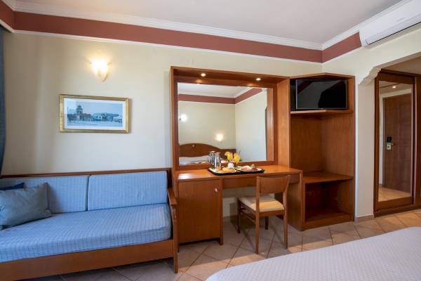 Ein Zimmer im Hydramis Palace Beach Resort mit einem Sofa, einem Tisch, einem Stuhl und einem Fernseher.