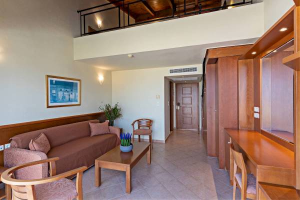 Innenbereich einer Suite im Hydramis Palace Beach Resort mit Sofa, Tisch, Stühlen und Dekor.
