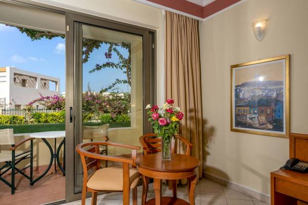 Balkon des Hydramis Palace Beach Resorts mit Tisch, Stühlen und Blumen.