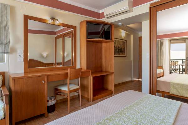 Ein modernes Hotelzimmer mit einem Schreibtisch, einem Stuhl, einem Spiegel und einem Fernseher im Hintergrund.