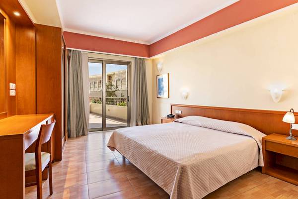 Ein modernes Hotelzimmer im Hydramis Palace Beach Resort mit einem Bett, Schreibtisch und Balkon.