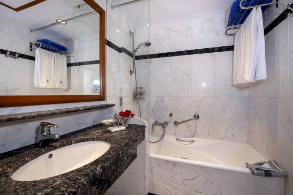 Hydramis Palace Beach Resort Badezimmer mit Badewanne, Spiegel und Handtüchern.