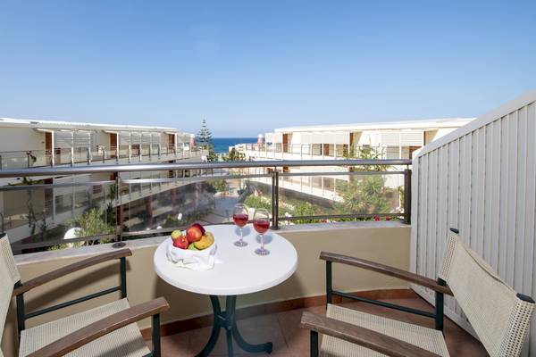 Ein Balkon des Hydramis Palace Beach Resorts mit Meerblick, zwei Gläsern Wein und einem Tisch mit Früchten.