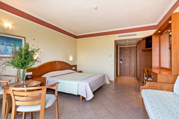 Ein Hotelzimmer im Hydramis Palace Beach Resort mit Bett, Tisch und Stühlen.