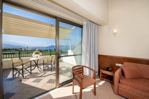 Balkon mit Meerblick im Hydramis Palace Beach Resort, mit Tisch, Stühlen und Aussicht auf die Berge.