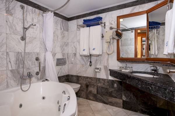 Das Badezimmer im Hydramis Palace Beach Resort mit Badewanne, Dusche, Toilette und Waschbecken.