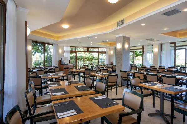 Innenbereich des Restaurants im Hydramis Palace Beach Resort mit vielen gedeckten Tischen und Stühlen.