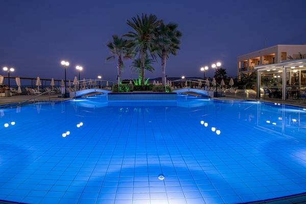 Nachtansicht des beleuchteten Swimmingpools des Hydramis Palace Beach Resorts mit Palmen und Sonnenliegen