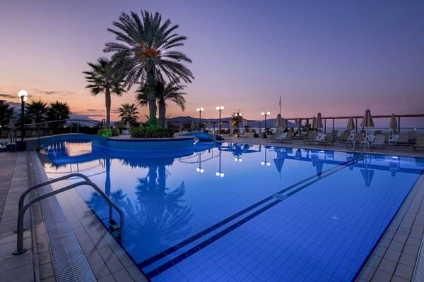 Abendansicht des Swimmingpools im Hydramis Palace Beach Resort mit blauem Wasser und Sonnenschirmen.