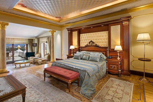 Innenansicht des Schlafzimmers im Titanic Mardan Palace Hotel mit großem Bett, Nachttischen und einem Ausblick auf die Stadt.