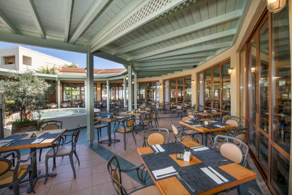 Innenansicht des Restaurants im Hydramis Palace Beach Resort mit Tischen und Stühlen.