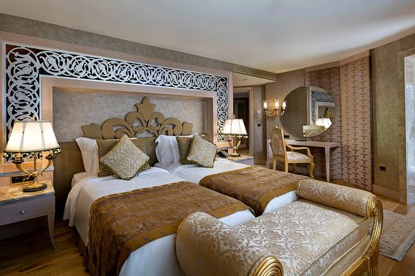 Zwei Betten im eleganten Hotelzimmer des Titanic Mardan Palace mit goldenen und weißen Bezügen.