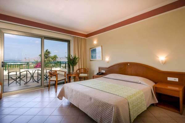 Ein modernes Hotelzimmer im Hydramis Palace Beach Resort mit einem Doppelbett, einem Balkon und Meerblick.
