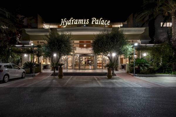 Außenansicht des Hydramis Palace Beach Resorts bei Nacht mit beleuchtetem Eingang und geparktem Auto.