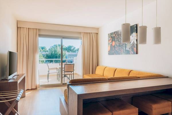 Wohnbereich des Iberostar Waves Pinos Park Hotels mit Sofa, Tisch, Fernseher und Balkon