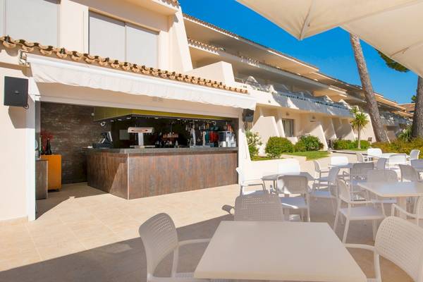 Außenbereich des Iberostar Waves Pinos Park Hotels mit Bar und Tischen unter Schirmen.