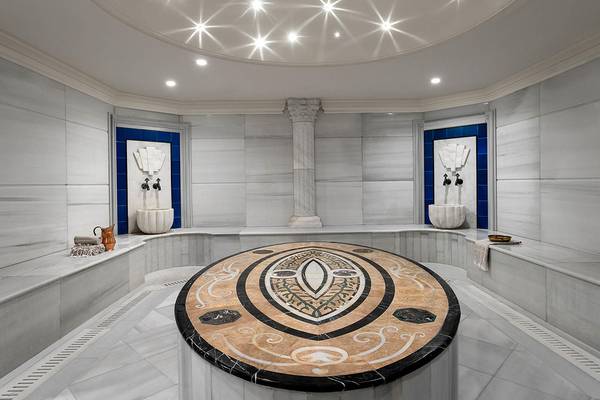 Innenansicht der Sauna im Titanic Mardan Palace mit weißen Wänden, einer zentralen Marmorplatte und Sternen an der Decke.