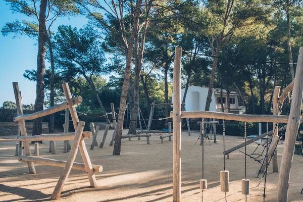 Außenbereich des Iberostar Waves Pinos Park mit Klettergerüsten und Holzkonstruktionen inmitten von Bäumen.