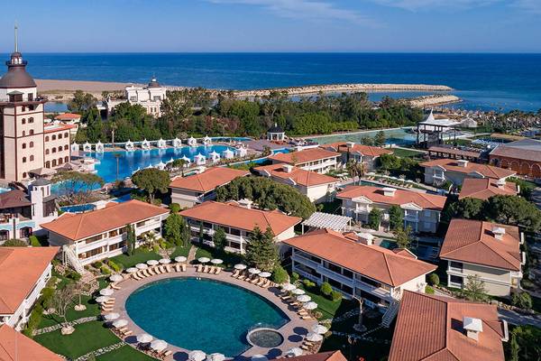 Luftaufnahme des Titanic Mardan Palace Hotels mit mehreren Swimmingpools, Gebäuden und Meer im Hintergrund.