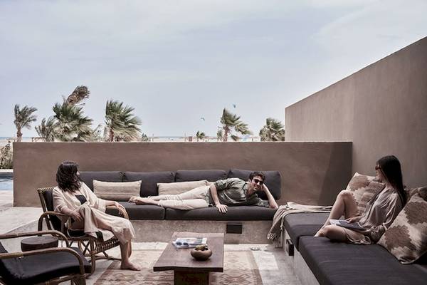 Personen entspannen auf der Terrasse des Casa Cook El Gouna Hotels, umgeben von Palmen und Blick aufs Meer.