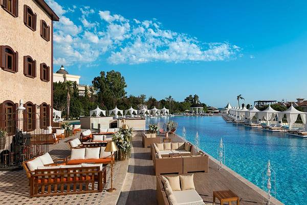 Außenbereich des Titanic Mardan Palace Hotels mit einem langen Pool und vielen Lounge-Bereichen.