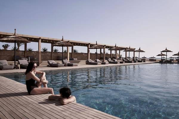 Zwei Personen sitzen am Rand des Pools im Hotel Casa Cook El Gouna.