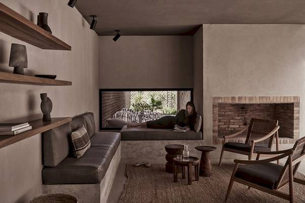 Innenbereich des Casa Cook El Gouna Hotels mit Frau auf Liege, Couch, Holztischen und Sesseln.