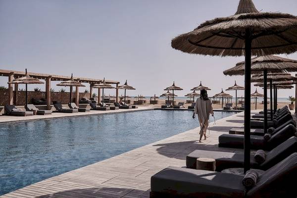 Außenbereich des Casa Cook El Gouna Hotels mit Pool, Sonnenschirmen und Liegestühlen.