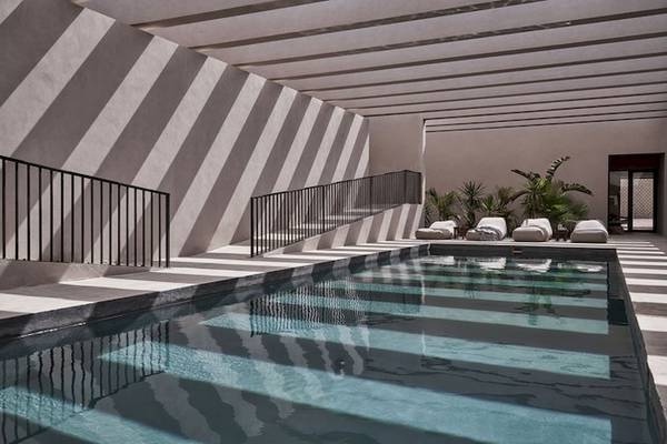 Innenpool des Casa Cook El Gouna Hotels mit stilvollen schwarzen Geländern und umgeben von Loungemöbeln.