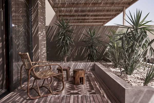 Terrasse mit Sitzecke im Casa Cook El Gouna Hotel, umgeben von Pflanzen und Holzmöbeln.