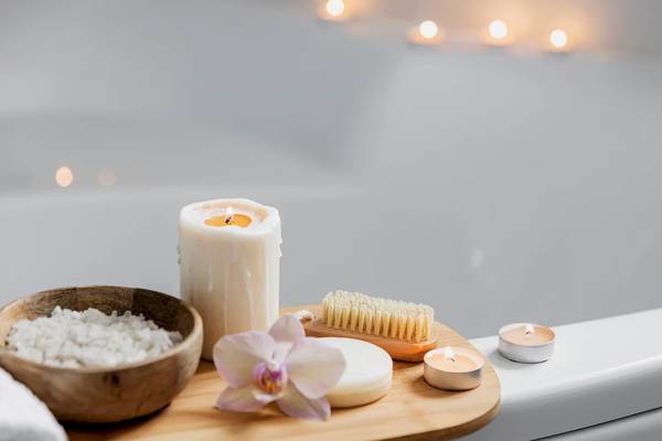 Eine Badewanne mit Kerzen, Seife, einer Orchidee und einem Handschuh in einem ruhigen Badezimmer.