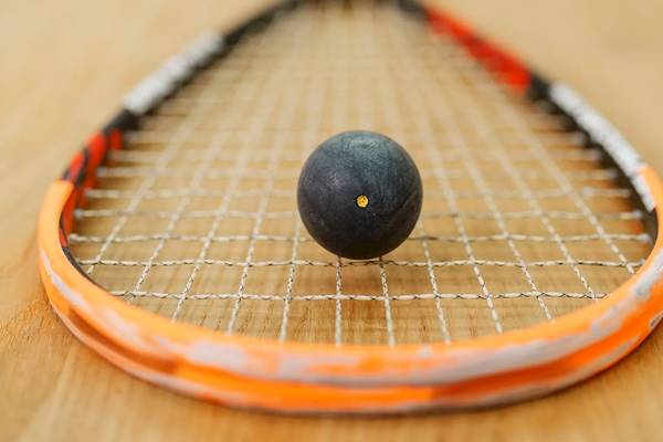 Tennisschläger mit Ball auf Holzboden, Ball mit gelber Mitte.