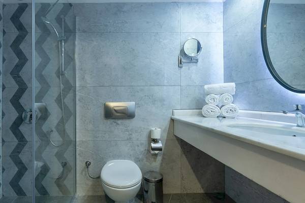 Das Badezimmer im Sunrise Queen Luxury Hotel mit einer Duschkabine, einem Waschbecken und einem Spiegel.