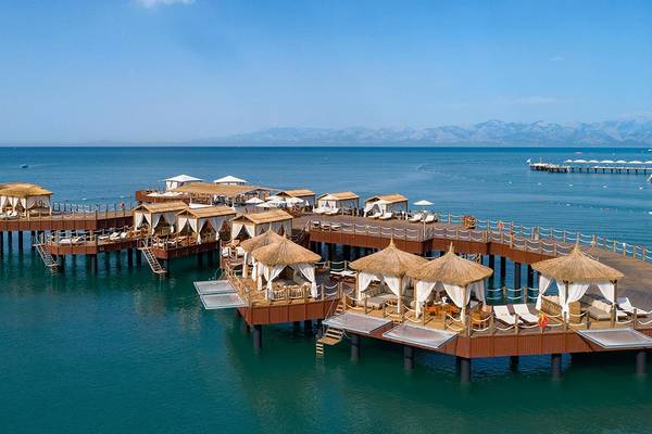 Luftaufnahme des Titanic Mardan Palace Hotels mit Wasserbungalows und Loungebereichen am Meer