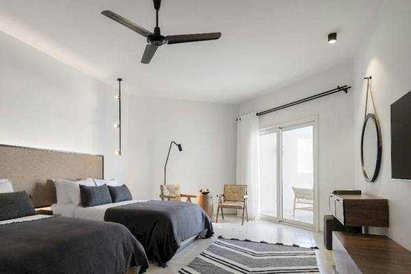 Doppelbettzimmer im Serry Beach Resort mit weißen Wänden, einer großen Glastür und einem Ventilator an der Decke.