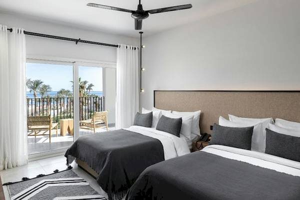 Schlafzimmer im Serry Beach Resort mit zwei Betten, einem Balkon und Meerblick.