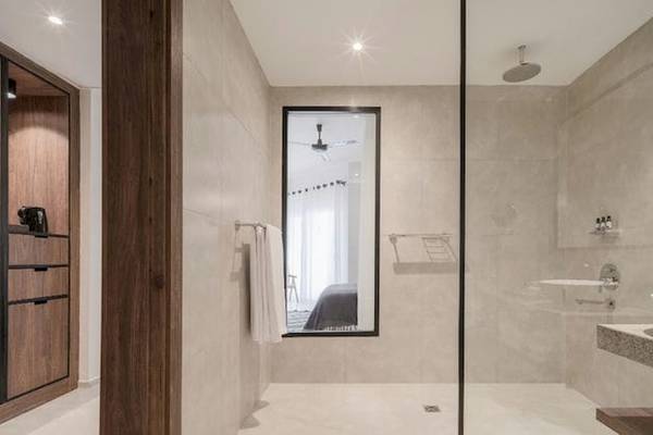 Ein modernes Badezimmer im Serry Beach Resort mit einer Duschkabine, einem Waschbecken, einem Spiegel und Holzmöbeln.