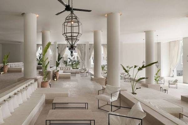 Serry Beach Resort Lounge Bereich mit weißen Möbeln, Säulen, Pflanzen und Deckenventilatoren.