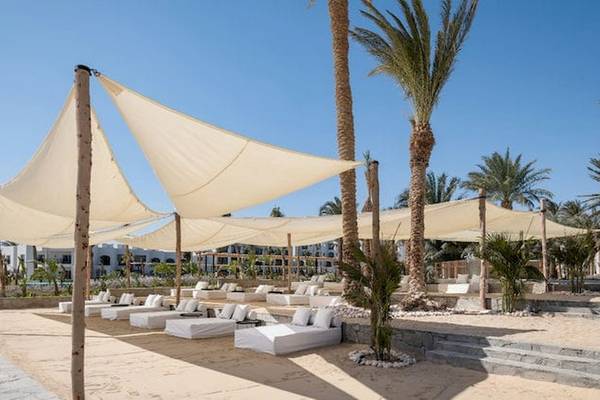 Serry Beach Resort Strandlounge Bereich mit weißen Sonnenliegen und Sonnensegeln