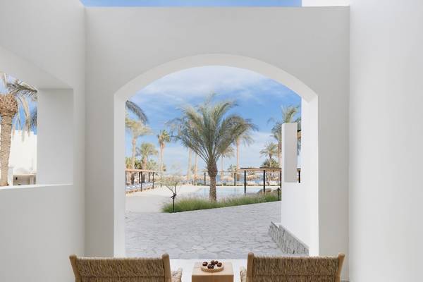 Innenansicht des Serry Beach Resorts mit Blick durch einen Bogen auf eine Terrasse mit zwei Stühlen und einem Tisch