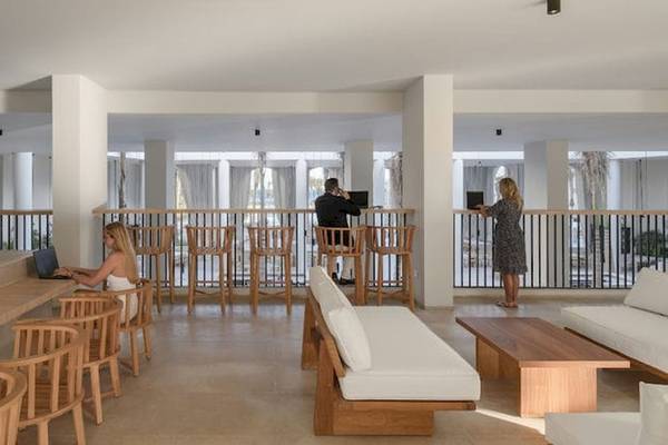 Lounge-Bereich im Serry Beach Resort mit Personen, die an Laptops arbeiten und eine Person, die auf dem Balkon steht.