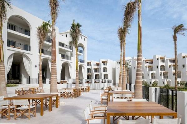 Serry Beach Resort Außenterrasse mit Tischen und Stühlen und Palmen.
