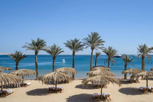 Serry Beach Resort Strand mit Palmen und Sonnenhuten vor blauem Wasser